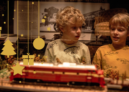 To gutter som kikker med nysgjerrighet på modelljernbanen i utstillingen